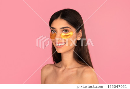 Smiling young woman with golden under-eye patches looking to side 133047931