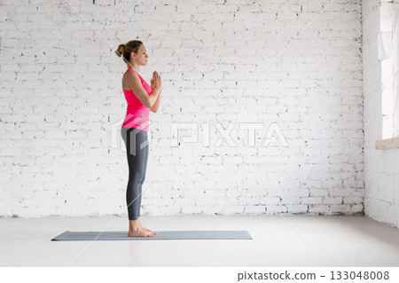 Yoga, start position. Caucasian fit woman in sportswear practice indoor in loft studio. Yoga, start position. Caucasian fit woman in sportswear practice indoor in loft studio. 133048008