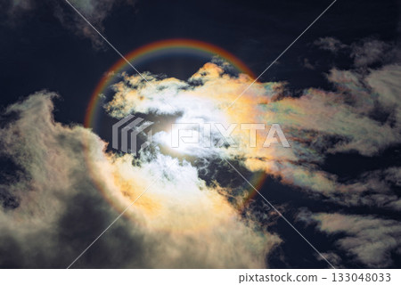 A captivating rainbow solar halo phenomenon with the sun centered in a circular rainbow against a cloudy sky A captivating rainbow solar halo phenomenon with the sun centered in a circular rainbow against a cloudy sky 133048033
