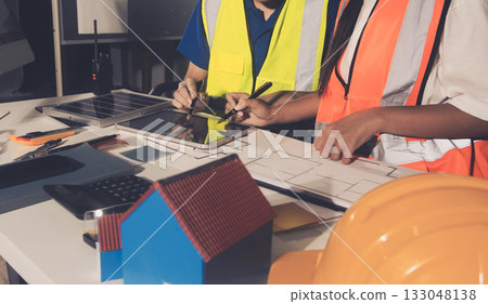 Closeup of team of industrial engineers meeting analyze machinery blueprints consult project on table in manufacturing factory. Working in manufacturing plant or production plant. Closeup of team of industrial engineers meeting analyze machinery blueprints consult project on table in manufacturing factory. Working in manufacturing plant or production plant. 133048138