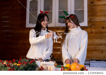 The two women are preparing a festive cake together for Christmas 133048642