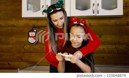 The mother and daughter are happily baking Christmas cookies together The mother and daughter are happily baking Christmas cookies together 133048674
