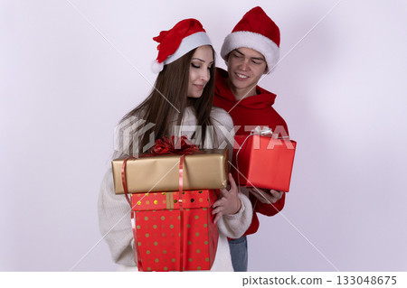 A happy couple wearing Santa hats is holding Christmas gifts A happy couple wearing Santa hats is holding Christmas gifts 133048675