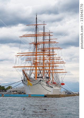 Vertical photo of the sailing ship Kaiwomaru anchored under a cloudy sky 133048770