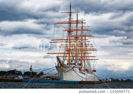 A view of the sailing ship Kaiwomaru anchored under a cloudy sky and the Tateyama mountain range 133048771