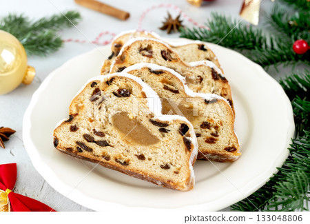 Christmas marzipan stollen with raisins, powdered sugar on white background. Christmas food. Christmas marzipan stollen with raisins, powdered sugar on white background. Christmas food. 133048806