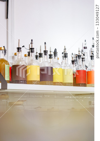 Colorful bottles with various liquids displayed on a shelf in a bright cafe setting Colorful bottles with various liquids displayed on a shelf in a bright cafe setting 133049127