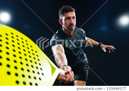 Serious athlete practicing paddle sports in a dark indoor facility with bright lights Serious athlete practicing paddle sports in a dark indoor facility with bright lights 133049177
