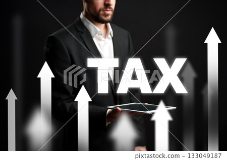 Businessman presenting tax growth concept using a tablet with upward arrows in background 133049187