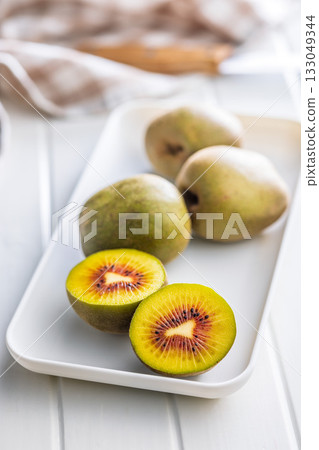 Red kiwi fruit on plate on white table. 133049344