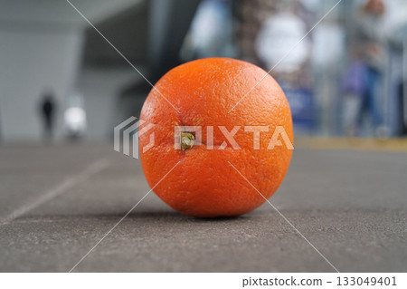 Orange lies on the pavement, people goes around Orange lies on the pavement, people goes around 133049401