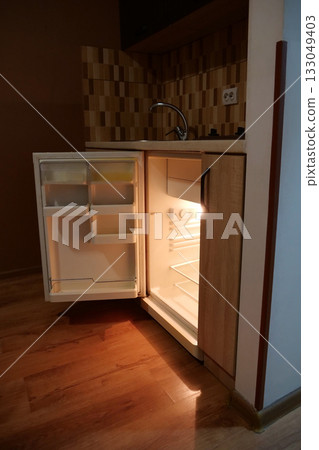 Empty mini fridge with open door in kitchen Empty mini fridge with open door in kitchen 133049403