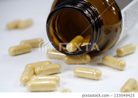 Yellow capsules scattered on the table and open glass jar for capsules. Overdose Yellow capsules scattered on the table and open glass jar for capsules. Overdose 133049425