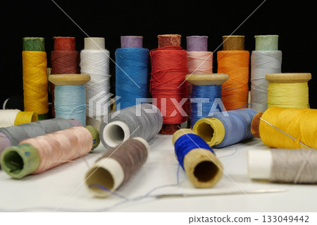 Spools with multi-colored threads on black background, close-up shot Spools with multi-colored threads on black background, close-up shot 133049442