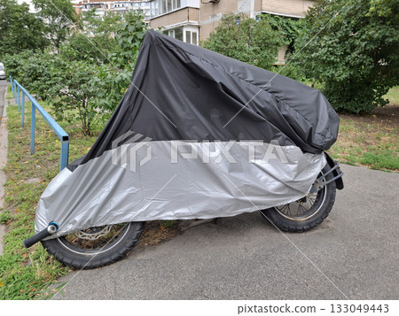 Black and gray cover on motorcycle parked in yard of house 133049443