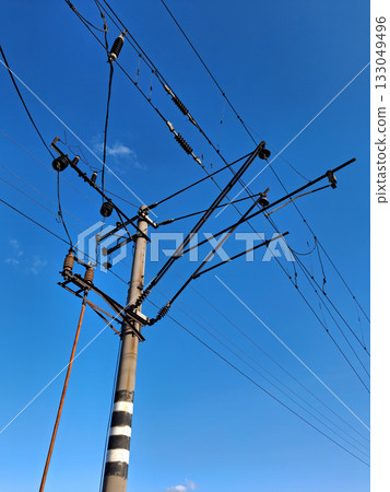 Wires, insulators and electrical equipment on a pole near railway tracks 133049496