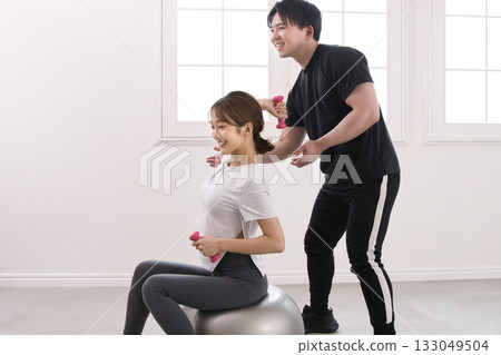 Young woman receiving training from a personal trainer Young woman receiving training from a personal trainer 133049504