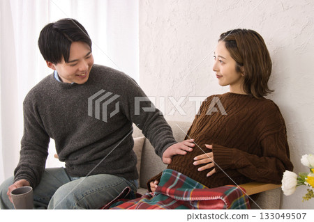一對年輕夫婦在沙發上休息，孕婦 133049507
