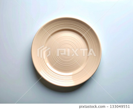 Elegant tableware. Ceramic plate with a classic beige design on a white background. Porcelain kitchenware. Close-up. Top view. 133049551