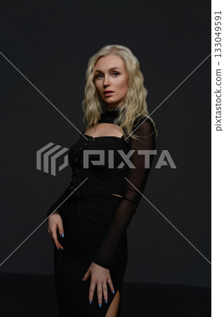Woman in black outfit poses confidently against a dark background at a studio photoshoot 133049591