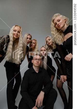 Group of friends posing together in stylish black outfits with long blonde hair 133049592