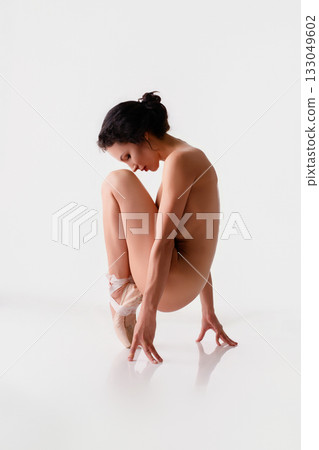 Ballerina in a graceful pose on pointe shoes against a minimalist backdrop 133049602