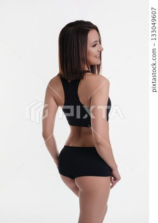 Woman in black activewear poses confidently in a studio setting with white background Woman in black activewear poses confidently in a studio setting with white background 133049607