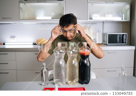 Chemist wearing safety glasses carefully preparing fertilizer for plants in kitchen, using various liquids and bottles, ensuring mixture safe and effective for promoting plant growth. Chemist wearing safety glasses carefully preparing fertilizer for plants in kitchen, using various liquids and bottles, ensuring mixture safe and effective for promoting plant growth. 133049785