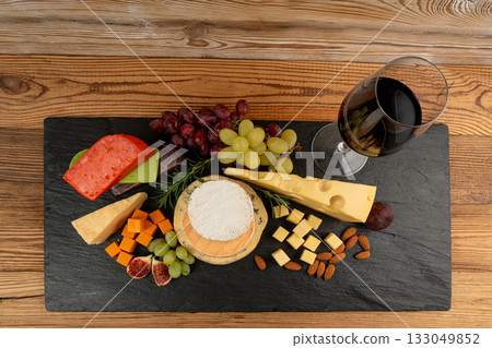 Cheese plate of color cheeses variety, yellow, white and blue gorgonzola platter with red wine glass Cheese plate of color cheeses variety, yellow, white and blue gorgonzola platter with red wine glass 133049852