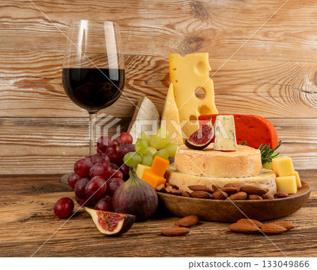 Cheese plate of color cheeses variety, yellow, white and blue gorgonzola platter with red wine glass 133049866