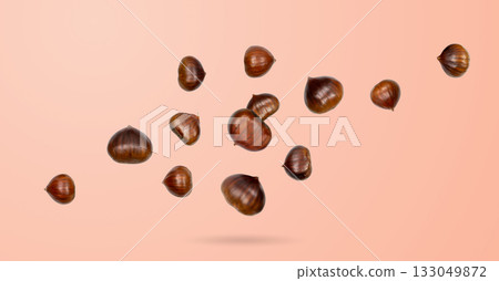 Falling edible sweet whole chestnuts, chest nuts in air on pink background Falling edible sweet whole chestnuts, chest nuts in air on pink background 133049872