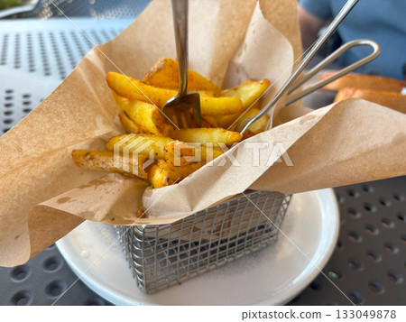 Fried chips sticks with peel in paper. Finger potato chips in restaurant Fried chips sticks with peel in paper. Finger potato chips in restaurant 133049878
