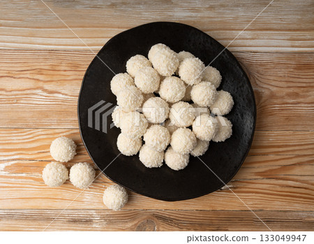 Coconut candies pile, coco ball. White truffle ball, indian ladoo or laddu with sweet cream and coco Coconut candies pile, coco ball. White truffle ball, indian ladoo or laddu with sweet cream and coco 133049947