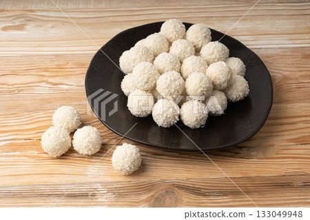 Coconut candies pile, coco ball. White truffle ball, indian ladoo or laddu with sweet cream and coco 133049948