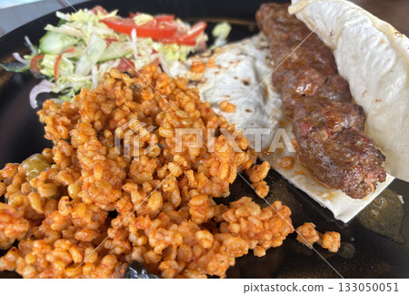 Turkish chicken kebab with bulgur, salad and lavash close up 133050051