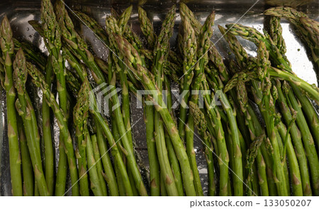 Cooked asparagus on a metal baking sheet. Roasted green vegetable for salad Cooked asparagus on a metal baking sheet. Roasted green vegetable for salad 133050207