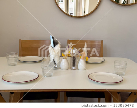 Minimalist table setting with plates and dried flowers near wall mirrors. Natural light, Scandinavian design, and serene dining mood. 133050478