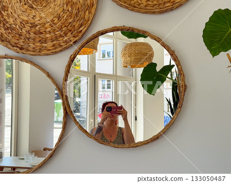 Woman taking mirror selfie in bright cafe interior. Natural light, reflection, and candid everyday lifestyle moment. 133050487