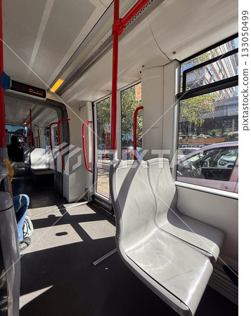 Tram interior with empty seats and bright daylight. Public transport, motion, and modern urban infrastructure. 133050499