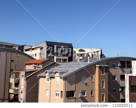 Modern residential buildings with bright roofs under blue sky. Urban living, architectural harmony, and modern design. 133050511