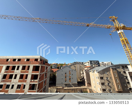Unfinished red brick apartment building under clear sky. Urban development, construction progress, and city growth. 133050513