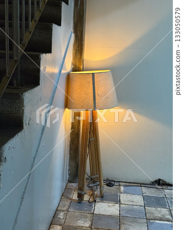 Floor lamp glowing softly near staircase corner. Warm light, evening calm, and cozy interior moment of quiet illumination. Floor lamp glowing softly near staircase corner. Warm light, evening calm, and cozy interior moment of quiet illumination. 133050579