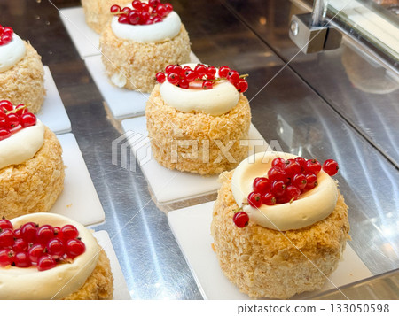 Raspberry and red currant cream tartlets in pastry shop. Elegant dessert styling, harmony of fruit color, and patisserie aesthetics. Raspberry and red currant cream tartlets in pastry shop. Elegant dessert styling, harmony of fruit color, and patisserie aesthetics. 133050598