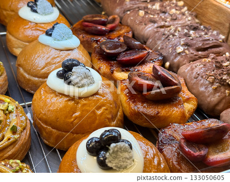 Assorted sweet buns with berries and cream topping. Modern bakery desserts, gourmet pastry, and sweet indulgence theme. Assorted sweet buns with berries and cream topping. Modern bakery desserts, gourmet pastry, and sweet indulgence theme. 133050605