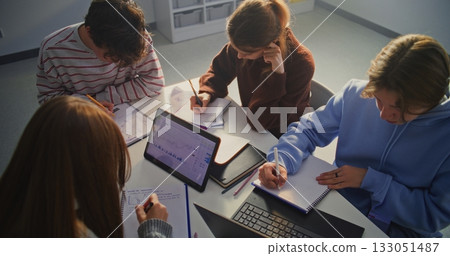 Diverse Study Group of Young Men and Women Leaning Over Table, Engaged in Academic Work Diverse Study Group of Young Men and Women Leaning Over Table, Engaged in Academic Work 133051487