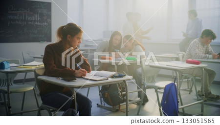 Worried Female Student Sits Quietly Apart From Group of Cheerful Classmates Using Phones and Talking Worried Female Student Sits Quietly Apart From Group of Cheerful Classmates Using Phones and Talking 133051565