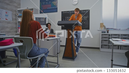 Student in Orange Hoodie Stands Behind Podium in Front of Classmates and Speaks Confidently Student in Orange Hoodie Stands Behind Podium in Front of Classmates and Speaks Confidently 133051632