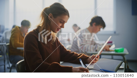 Young Female Student Smiles Brightly as Examines A Grade Report or Successful Exam Paper 133051640