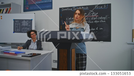 Energetic Female Student Presents Research Findings to Peers in Bright Classroom 133051653