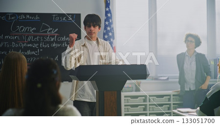 Young Student Stands on Podium and Delivers Passionate Speech to Classmates in Modern Auditorium Young Student Stands on Podium and Delivers Passionate Speech to Classmates in Modern Auditorium 133051700